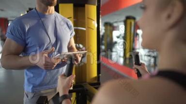 培训人员向客户介绍健身器材并讨论培训<strong>计划</strong>